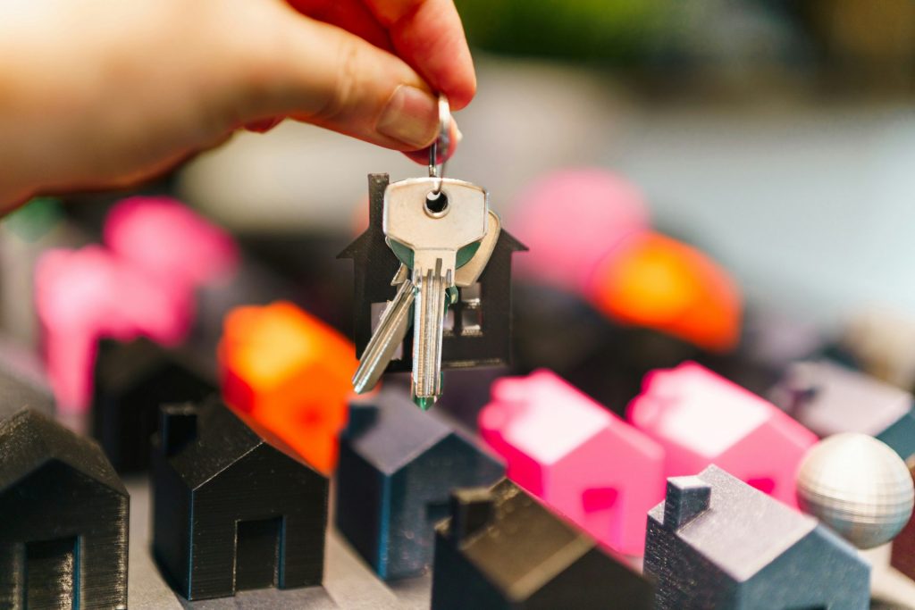 Hand holding house keys over miniature houses